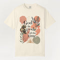 Beige t-shirt with floral design and 'God is good all the time' text on a white background