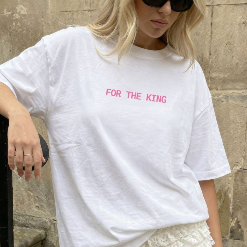 Person wearing a white t-shirt with 'FOR THE KING' text and lace shorts outdoors.