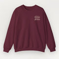 A maroon Everyday Faith sweatshirt with the text 'What's a Friend Jesus' printed in a light beige serif font on the left chest, displayed against a light gray background.