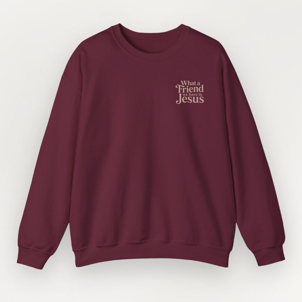 A maroon Everyday Faith sweatshirt with the text 'What's a Friend Jesus' printed in a light beige serif font on the left chest, displayed against a light gray background.