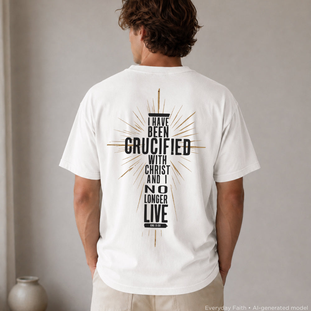 A man viewed from behind wearing a white Everyday Faith t-shirt with a large black graphic on the back featuring a cross and the text 'I HAVE BEEN CRUCIFIED WITH CHRIST AND I NO LONGER LIVE'.