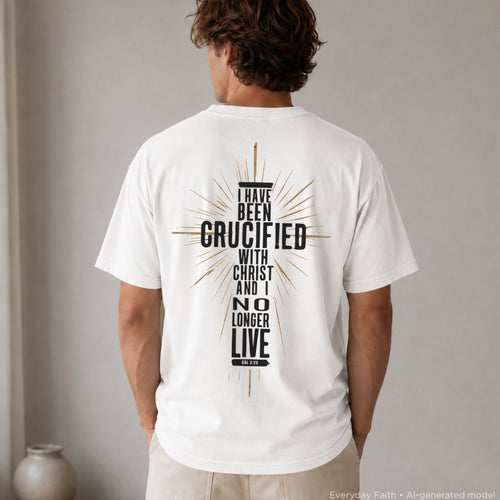 A man viewed from behind wearing a white Everyday Faith t-shirt with a large black graphic on the back featuring a cross and the text 'I HAVE BEEN CRUCIFIED WITH CHRIST AND I NO LONGER LIVE'.
