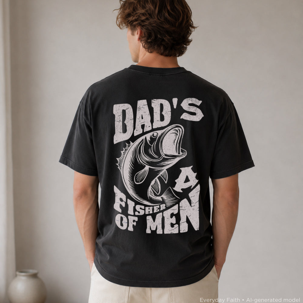 A man viewed from behind wearing a black Everyday Faith t-shirt with a large white graphic print that reads 'DAD'S A FISHER OF MEN' alongside a detailed bass illustration.