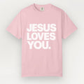 A light pink Everyday Faith short-sleeve crewneck t-shirt with the phrase 'JESUS LOVES YOU.' printed in bold white capital letters across the chest, displayed against a light gray background.