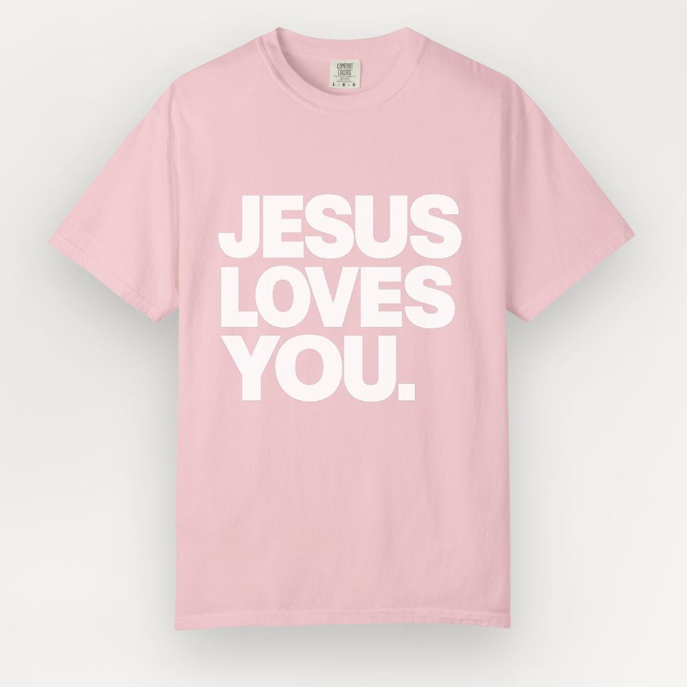 A light pink Everyday Faith short-sleeve crewneck t-shirt with the phrase 'JESUS LOVES YOU.' printed in bold white capital letters across the chest, displayed against a light gray background.