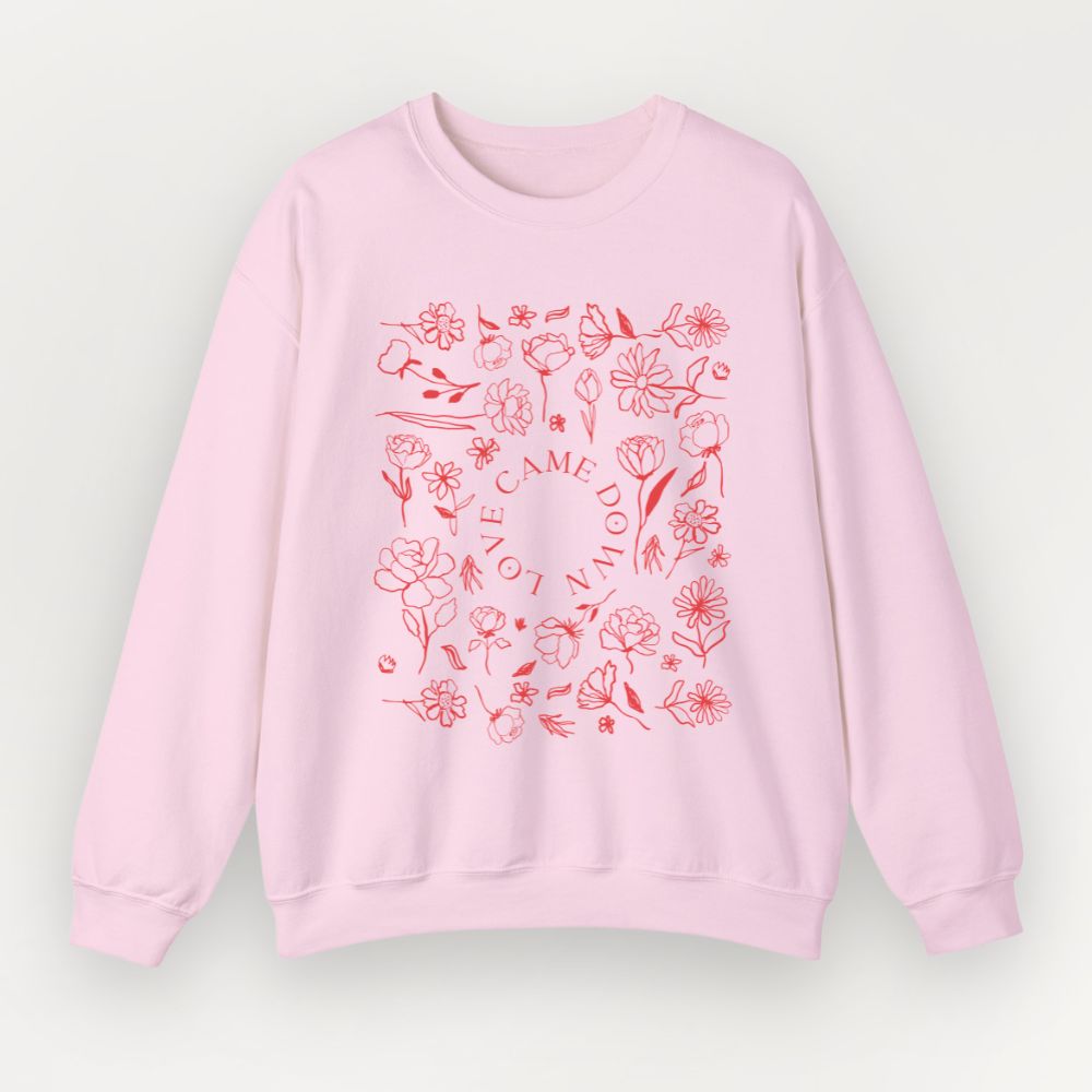 A light pink Everyday Faith crewneck sweatshirt featuring a red line-art floral graphic with the words 'LOVE CAME DOWN' arranged in a square pattern on the front, displayed against a light gray background.