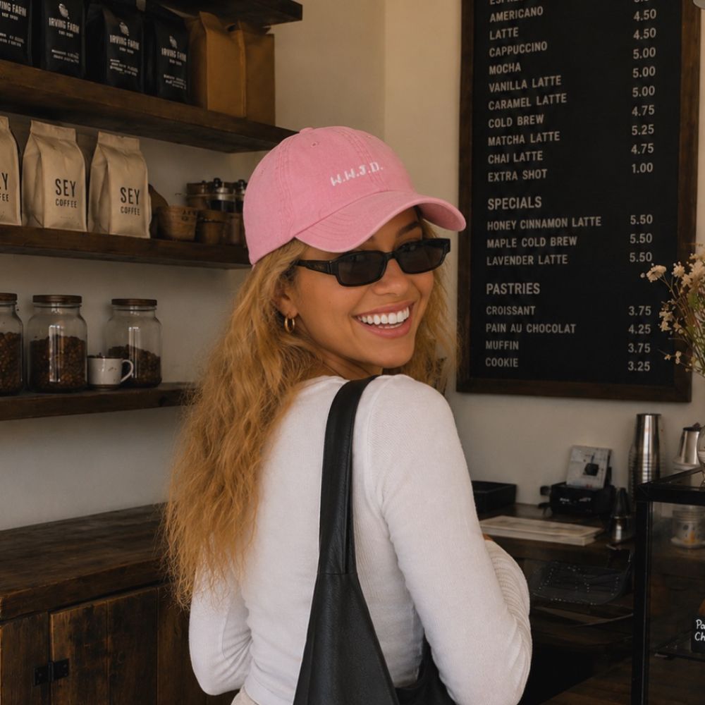 Woman wearing a pink cap and sunglasses in a coffee shop