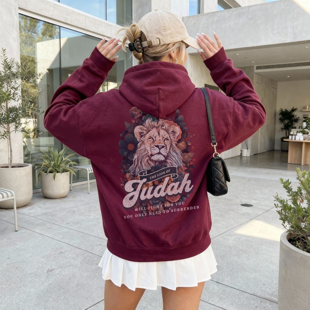 Person wearing a maroon hoodie with a lion graphic and text, standing in an outdoor setting.