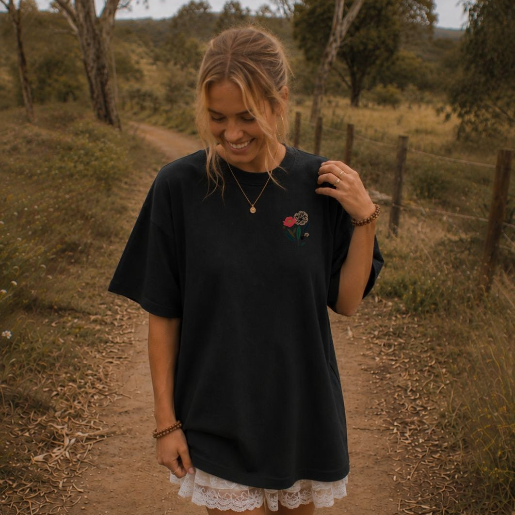 Woman wearing a black oversized shirt with a floral design in a rural setting