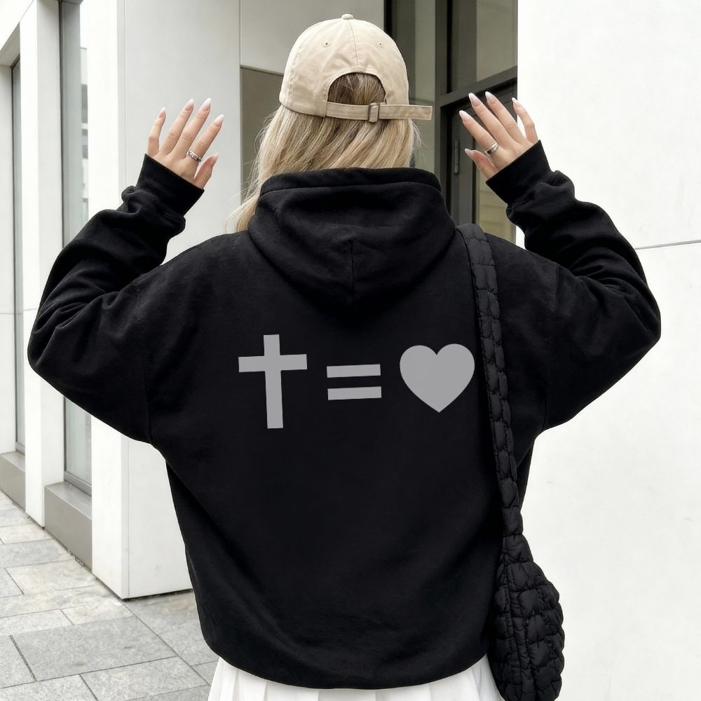 Person wearing a black hoodie with symbols on the back, standing in an urban setting.