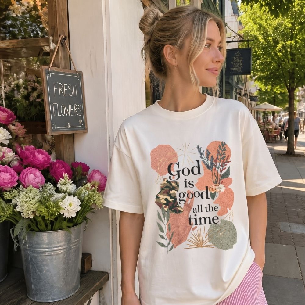 Woman wearing a 'God is good all the time' t-shirt in front of a flower shop.