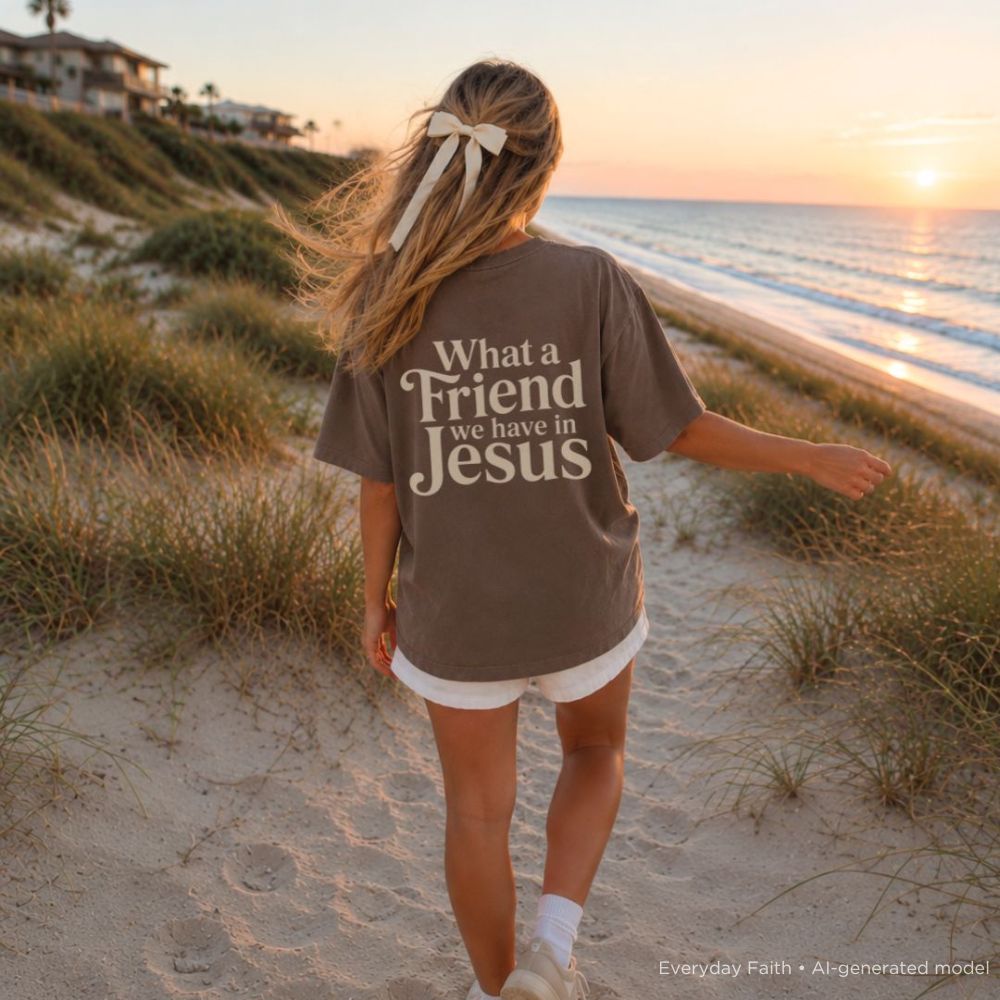 Person wearing a shirt with 'What a Friend we have in Jesus' on a beach at sunset.