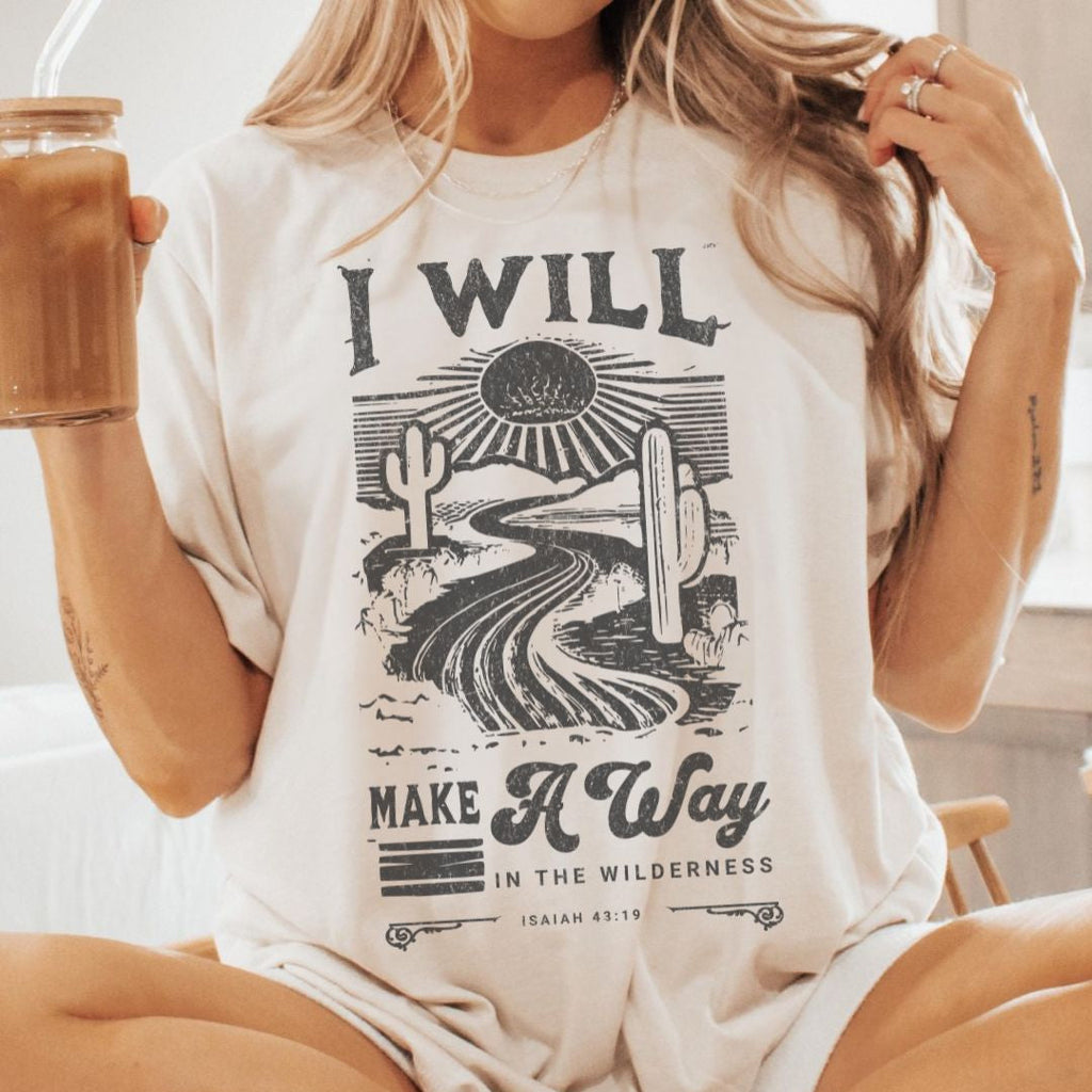 Woman wearing a Christian t-shirt with “I Will Make a Way” Isaiah 43:19 text design outdoors.